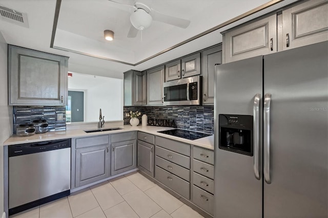 kitchen with visible vents, a raised ceiling, appliances with stainless steel finishes, gray cabinetry, and a sink