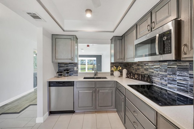 kitchen with appliances with stainless steel finishes, a sink, visible vents, and gray cabinetry