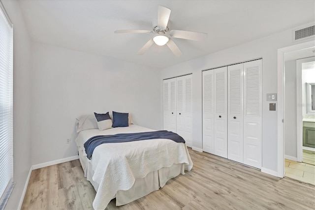 bedroom featuring multiple closets, baseboards, visible vents, and light wood finished floors