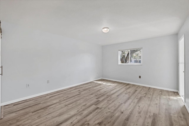 unfurnished room with baseboards and wood finished floors