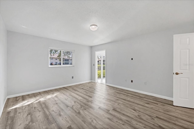 spare room with a textured ceiling, baseboards, and wood finished floors