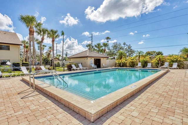 community pool with fence and a patio