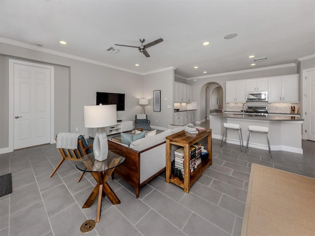 living room with arched walkways, crown molding, light tile patterned floors, recessed lighting, and ceiling fan