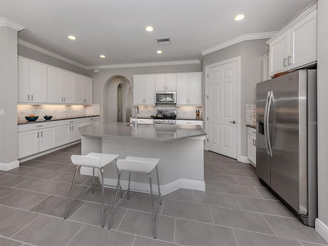 kitchen with visible vents, arched walkways, appliances with stainless steel finishes, dark tile patterned floors, and white cabinetry