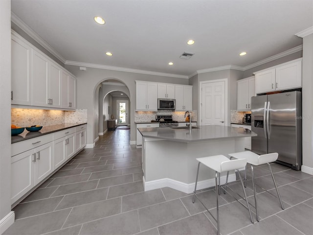 kitchen with stainless steel appliances, arched walkways, a sink, and light tile patterned floors