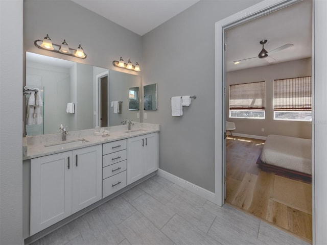 full bathroom with double vanity, ceiling fan, baseboards, and a sink