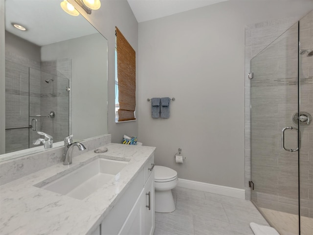 bathroom featuring toilet, a stall shower, baseboards, and vanity