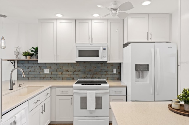 kitchen featuring pendant lighting, white appliances, white cabinets, and a sink