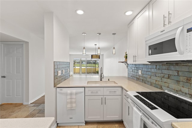 kitchen with white appliances, hanging light fixtures, light countertops, white cabinetry, and a sink