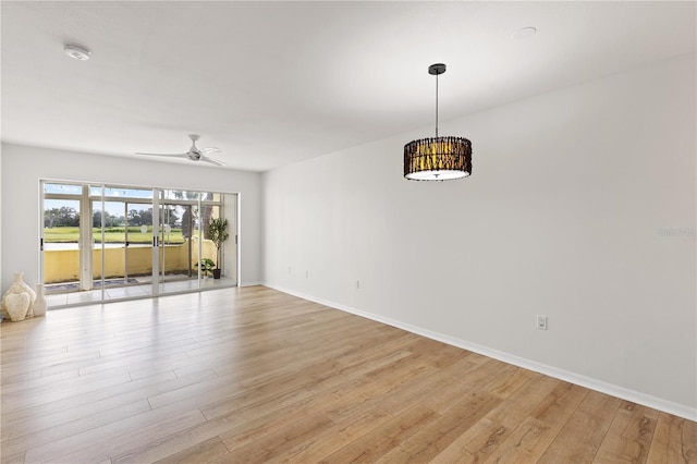 unfurnished room with light wood-type flooring, a ceiling fan, and baseboards