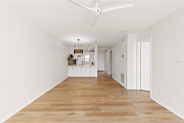 unfurnished living room featuring light wood-type flooring, visible vents, and baseboards