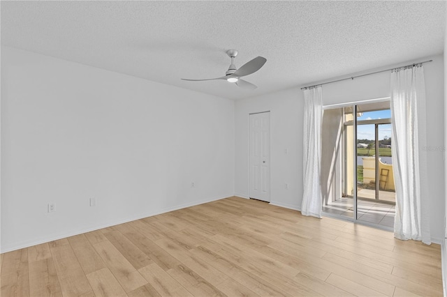 empty room with a ceiling fan, light wood-type flooring, a textured ceiling, and baseboards