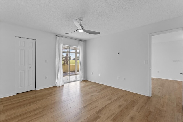 spare room featuring light wood-type flooring, a ceiling fan, and a textured ceiling