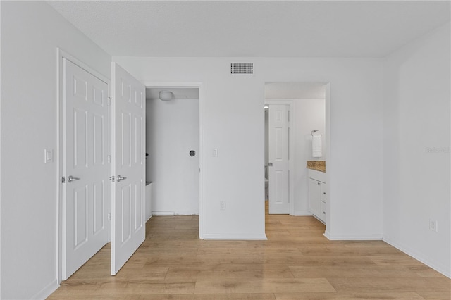 unfurnished bedroom with light wood-type flooring, visible vents, and baseboards