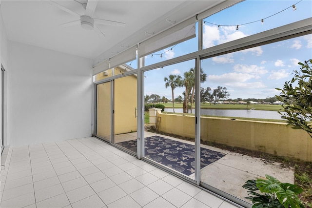 sunroom with ceiling fan and a water view