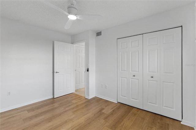 unfurnished bedroom featuring baseboards, visible vents, a textured ceiling, and light wood finished floors