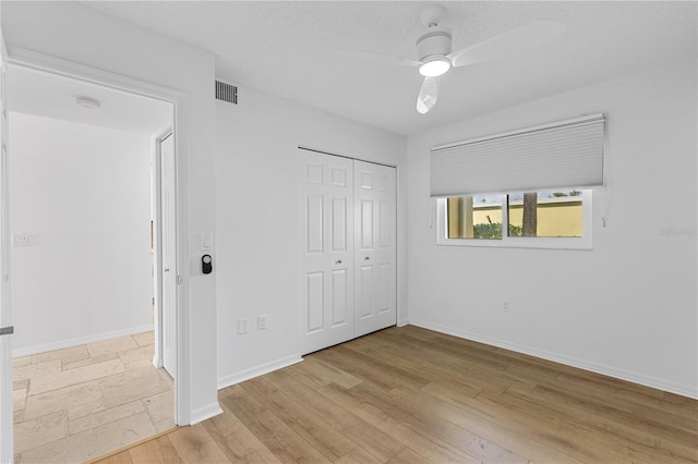 unfurnished bedroom featuring baseboards, visible vents, a ceiling fan, light wood-style floors, and a closet