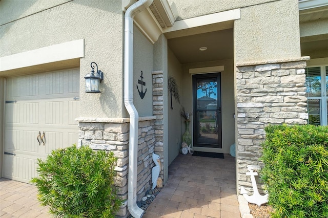 property entrance featuring a garage, stone siding, and stucco siding