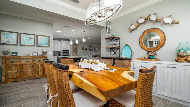 dining space with an inviting chandelier, wood tiled floor, visible vents, and crown molding