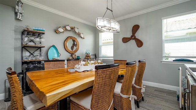 dining area with a chandelier, ornamental molding, wood finish floors, and baseboards