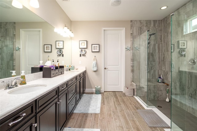 full bath with double vanity, a stall shower, a sink, and wood tiled floor