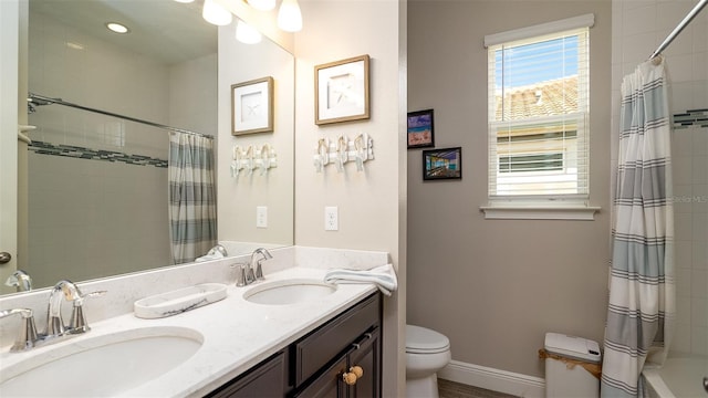 bathroom with baseboards, a sink, tiled shower / bath, and toilet