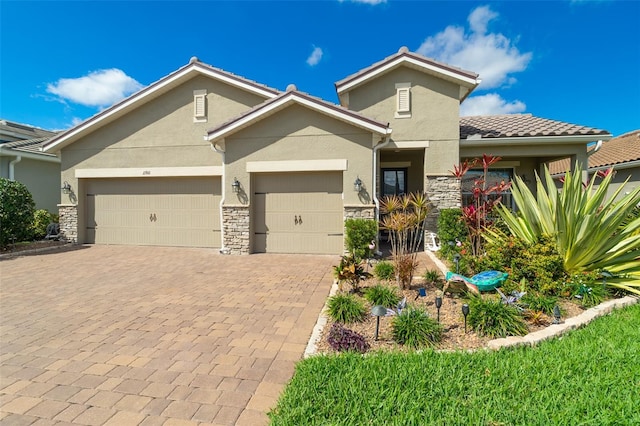 view of front facade featuring decorative driveway, stone siding, an attached garage, and stucco siding