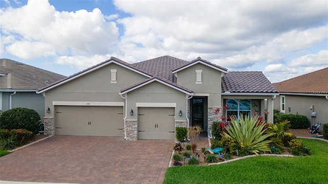 view of front of home featuring decorative driveway, stucco siding, a garage, stone siding, and a tiled roof