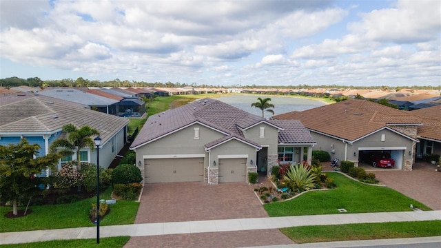 view of front of property with a garage, a residential view, a tiled roof, decorative driveway, and a front lawn