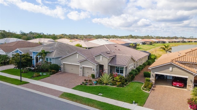 view of front of house featuring a garage, a tile roof, decorative driveway, a residential view, and a front lawn