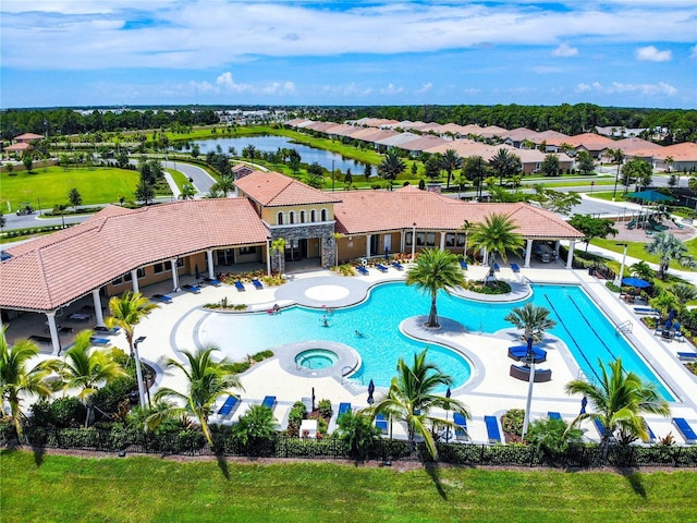 community pool featuring a patio, a water view, fence, and a hot tub