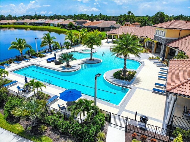 community pool featuring a patio, a community hot tub, a water view, fence, and a residential view