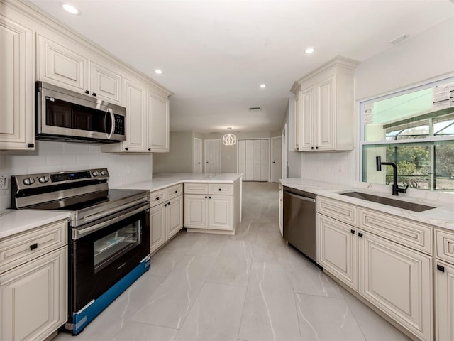 kitchen with marble finish floor, stainless steel appliances, tasteful backsplash, a sink, and a peninsula