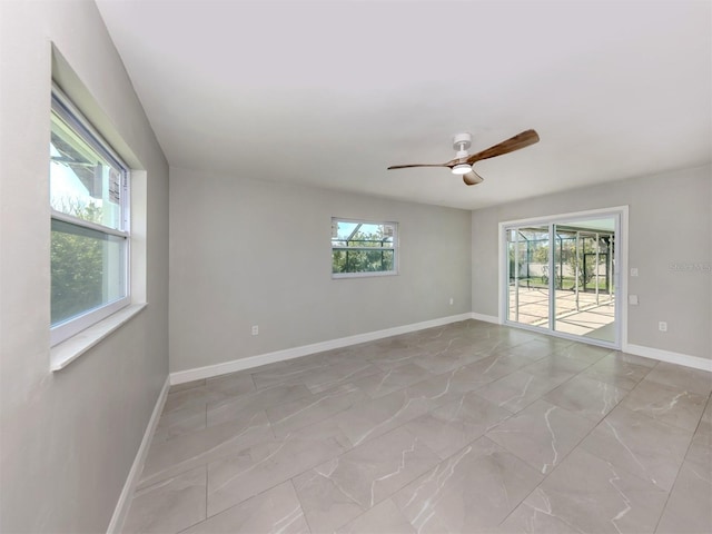 unfurnished room featuring marble finish floor, ceiling fan, and baseboards