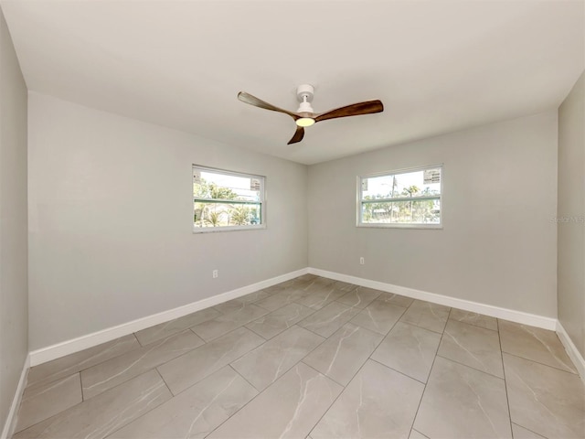 spare room featuring ceiling fan, plenty of natural light, and baseboards