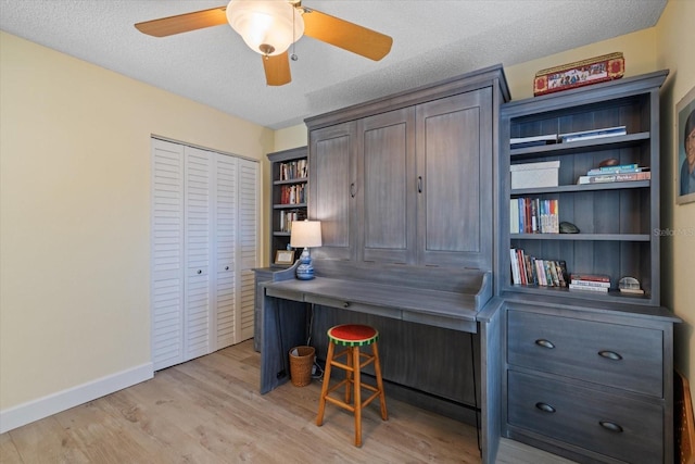 office space with light wood-type flooring, ceiling fan, a textured ceiling, and baseboards