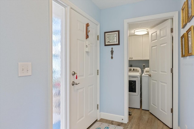 clothes washing area featuring baseboards, light wood-type flooring, cabinet space, and washer and dryer