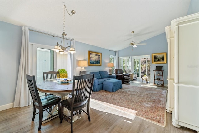 dining area featuring baseboards, vaulted ceiling, wood finished floors, and ceiling fan with notable chandelier