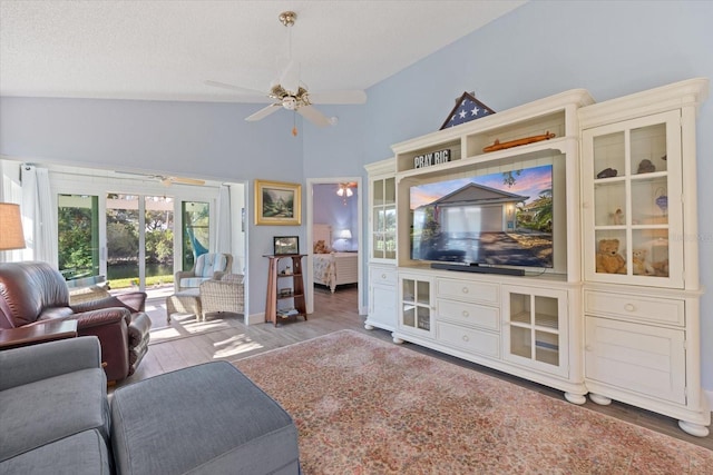 living area with a textured ceiling, a ceiling fan, vaulted ceiling, and wood finished floors