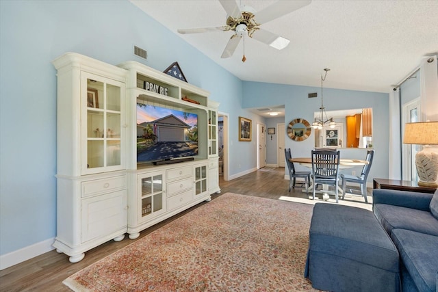 living room with lofted ceiling, visible vents, wood finished floors, and ceiling fan with notable chandelier