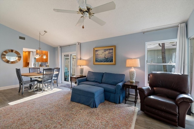 living room with lofted ceiling, a textured ceiling, wood finished floors, and visible vents