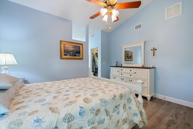 bedroom featuring a walk in closet, visible vents, baseboards, and wood finished floors