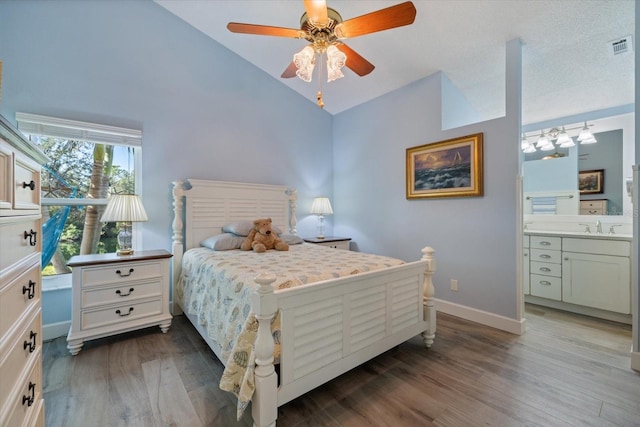 bedroom with lofted ceiling, dark wood-style flooring, a sink, visible vents, and baseboards