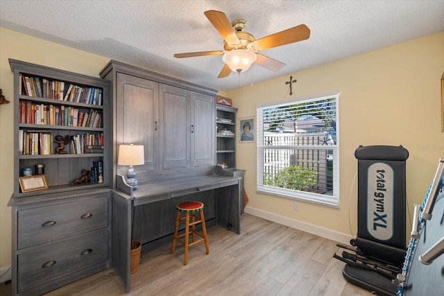 office space with light wood-style floors, baseboards, a ceiling fan, and a textured ceiling