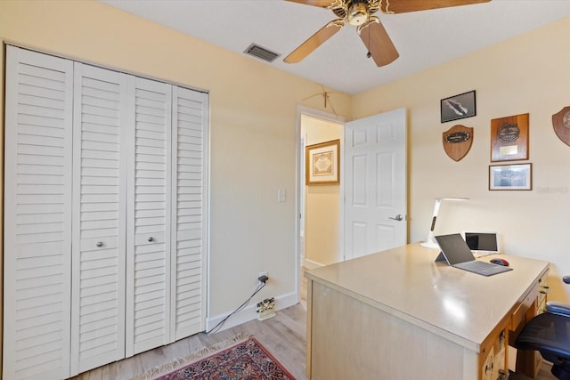 office area featuring light wood-type flooring, baseboards, visible vents, and a ceiling fan