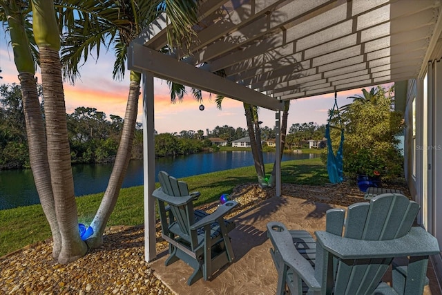 patio terrace at dusk with a lawn, a water view, and a pergola