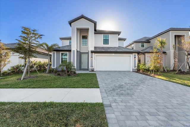 view of front of home featuring a front yard, decorative driveway, and an attached garage