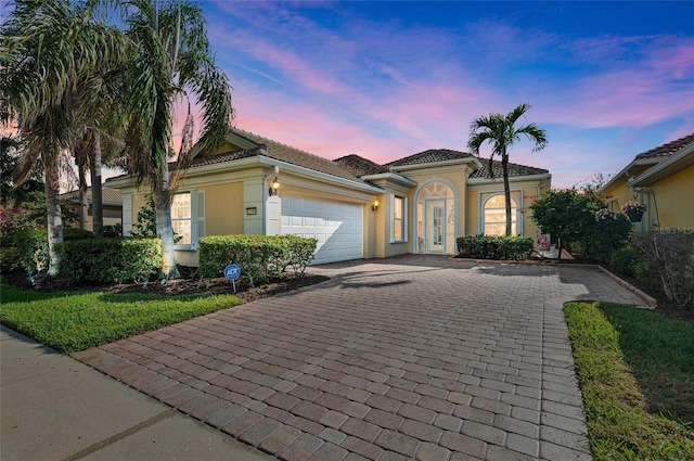 mediterranean / spanish-style house featuring a garage, a tile roof, and stucco siding