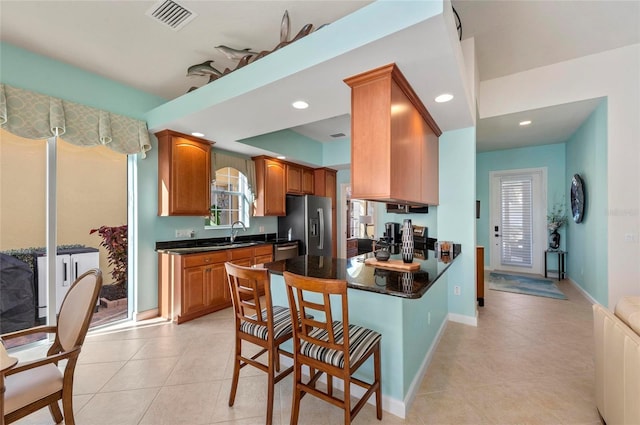 kitchen featuring dark countertops, recessed lighting, visible vents, a sink, and stainless steel fridge with ice dispenser