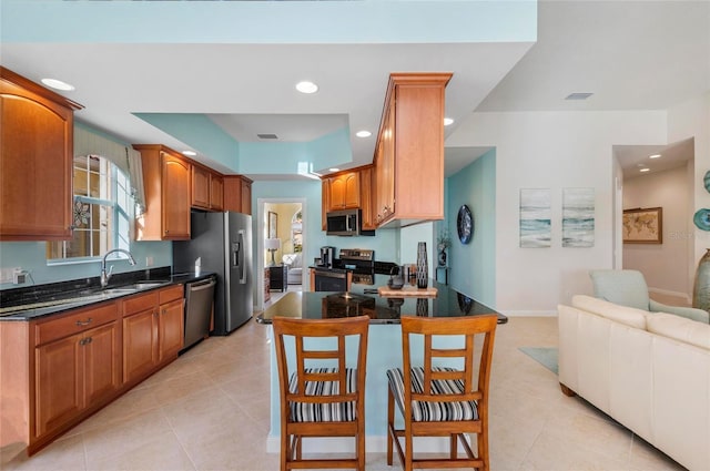 kitchen featuring light tile patterned floors, stainless steel appliances, a sink, and open floor plan